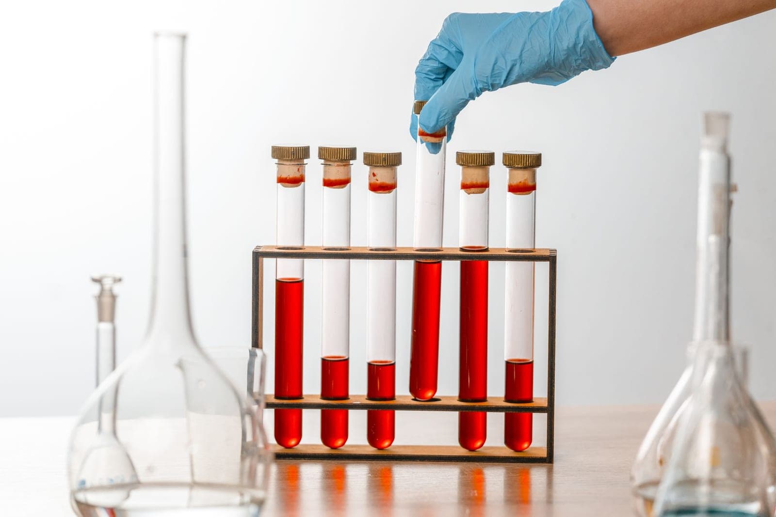 Gloved hands holding test tubes in a laboratory.