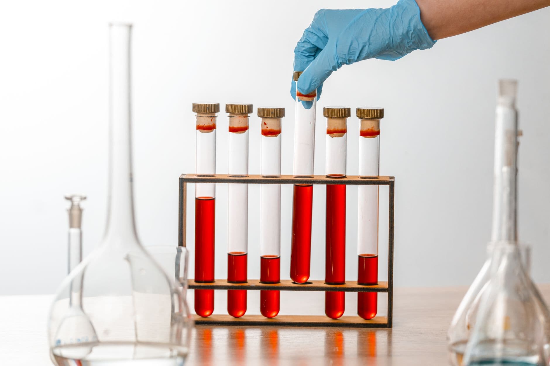 Gloved hands holding test tubes in a laboratory.