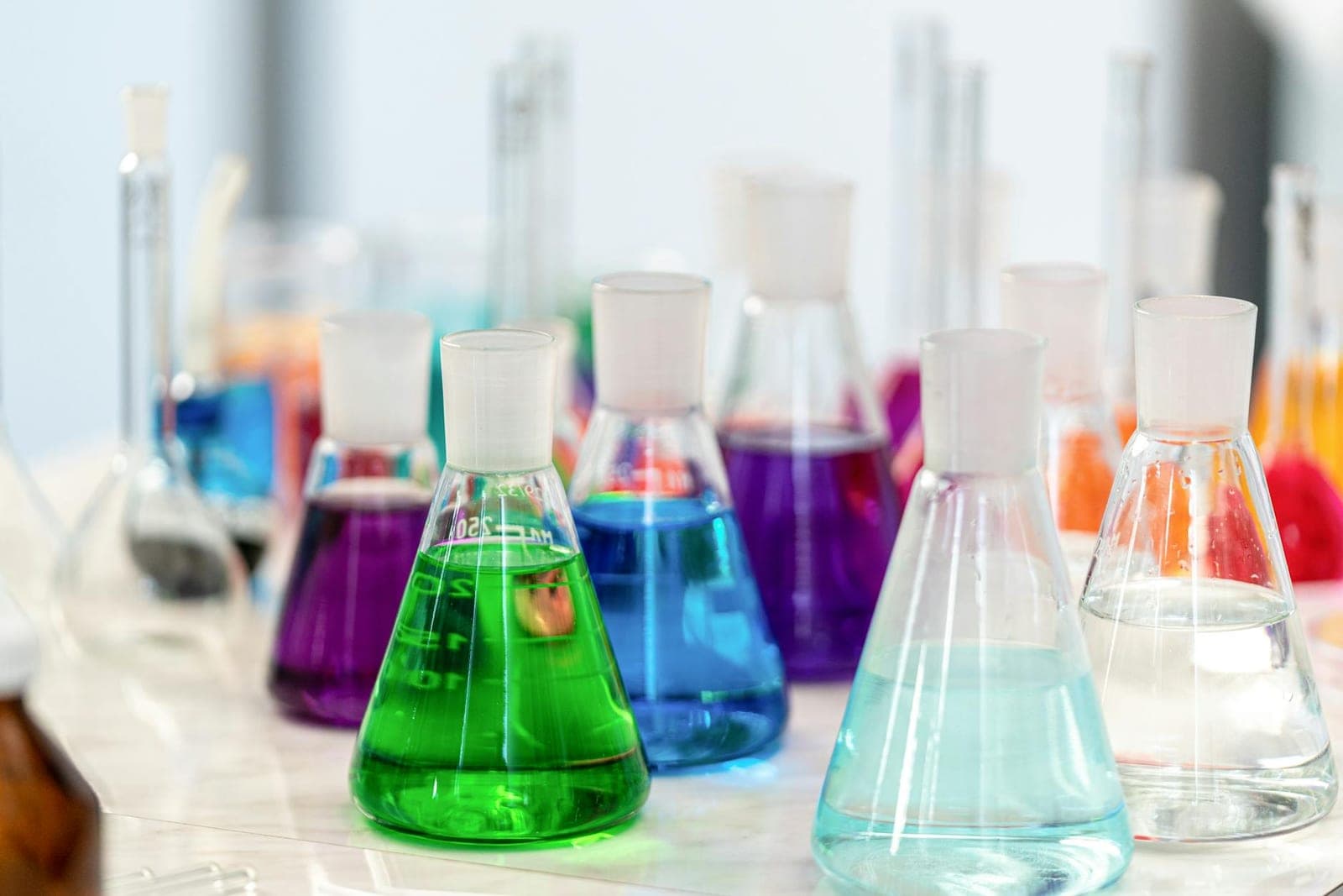 Colorful chemical solutions in laboratory glass beakers.