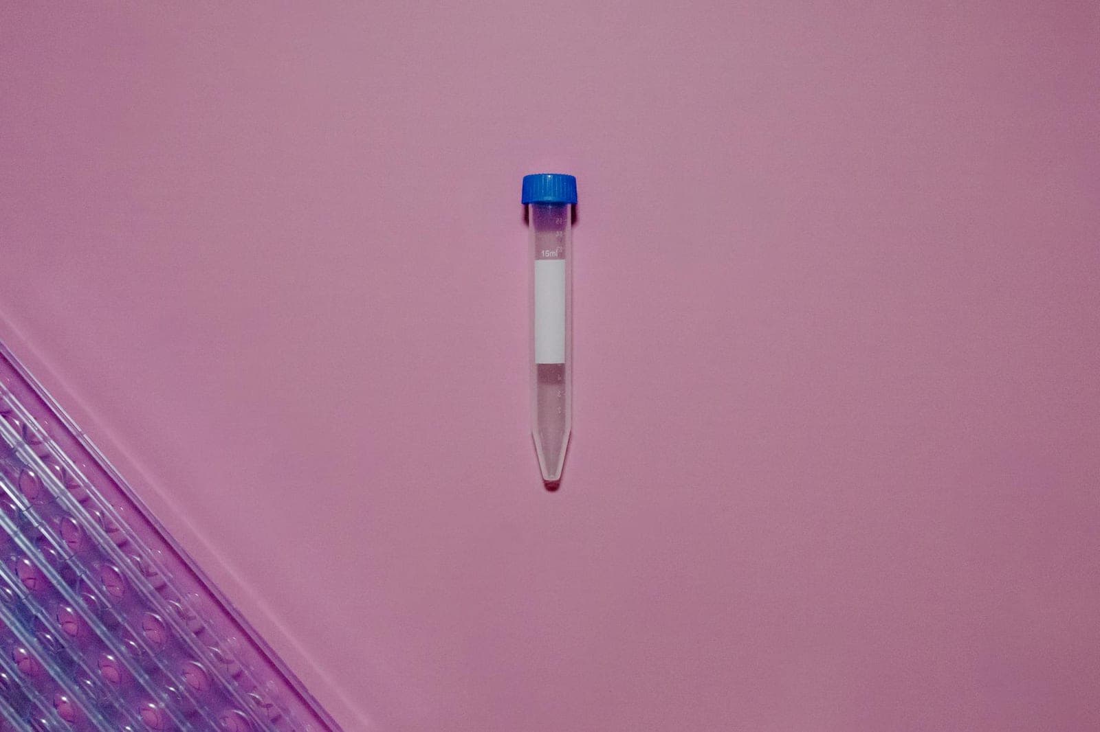 Laboratory test tube with blue cap on a clean surface.